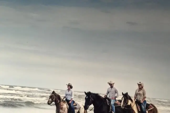a group of people riding a horse on a beach