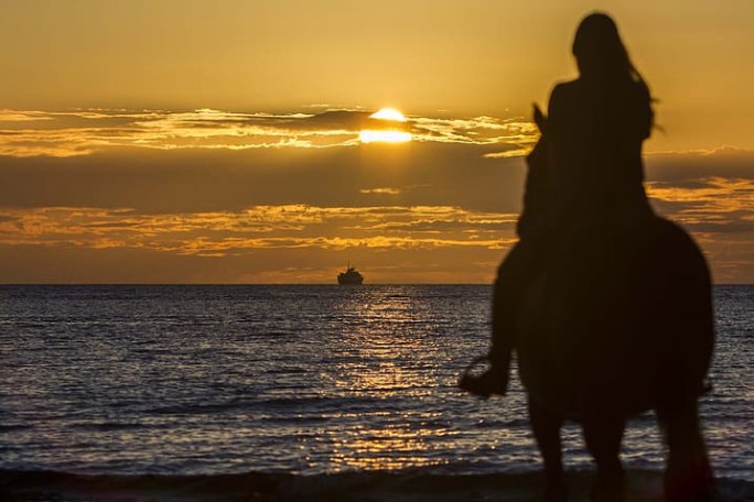 a person standing in front of a sunset over some water